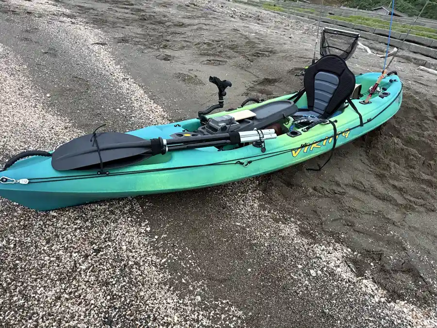 浜に置いた青緑色のバイキングカヤック忍と釣り道具